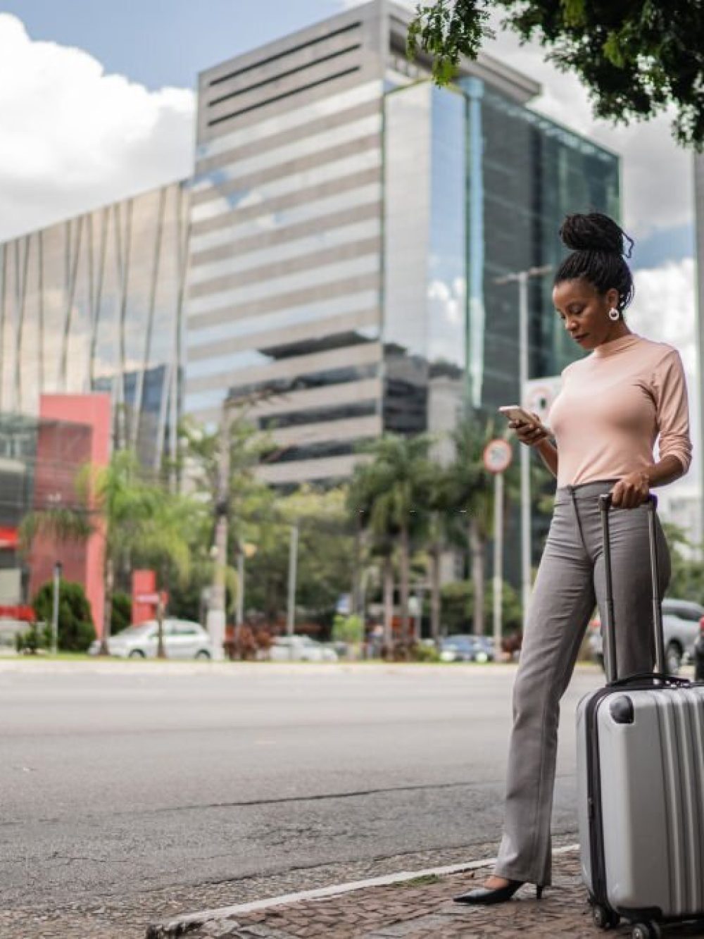 Business woman with luggage waiting for a taxi outdoors