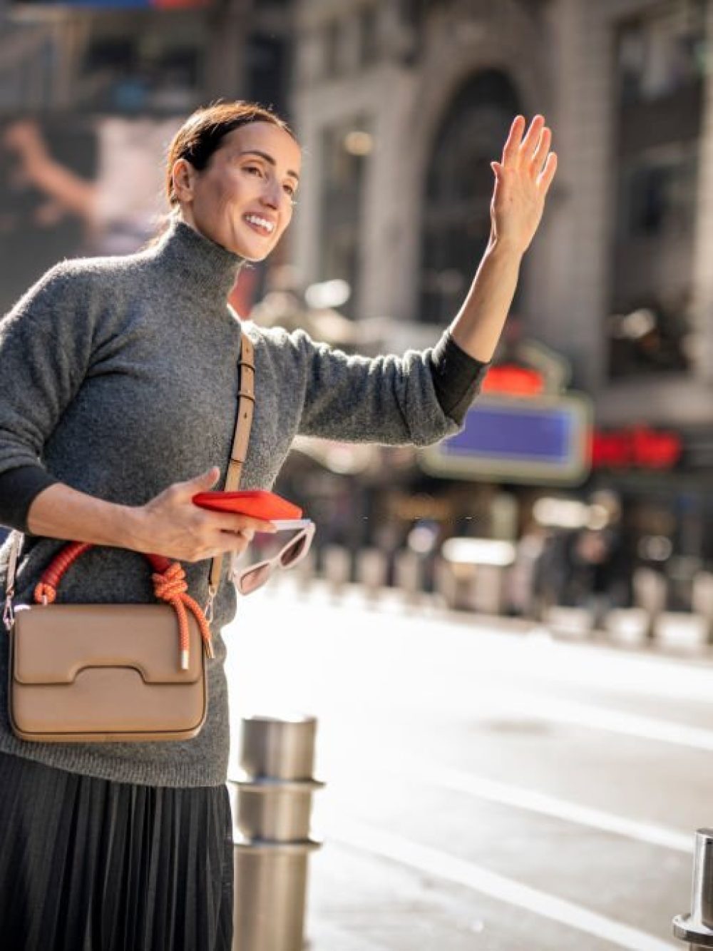 Adult woman seen on the street of Manhattan stopping Uber after waiting for it in front of a corporate building and she is heading to the Lower Manhattan for a business meeting.