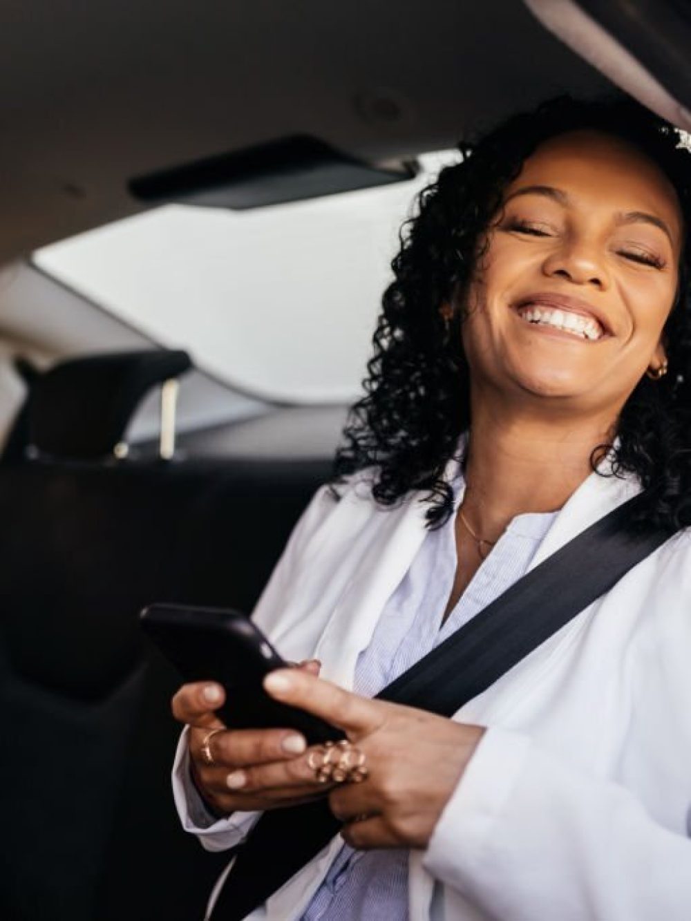 Happy businesswoman using smartphone in the car